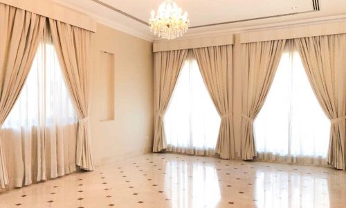 Luxury living room with beige carpets and a chandelier in a 4-bedroom villa for rent in Barbar, featuring a garden and pool.