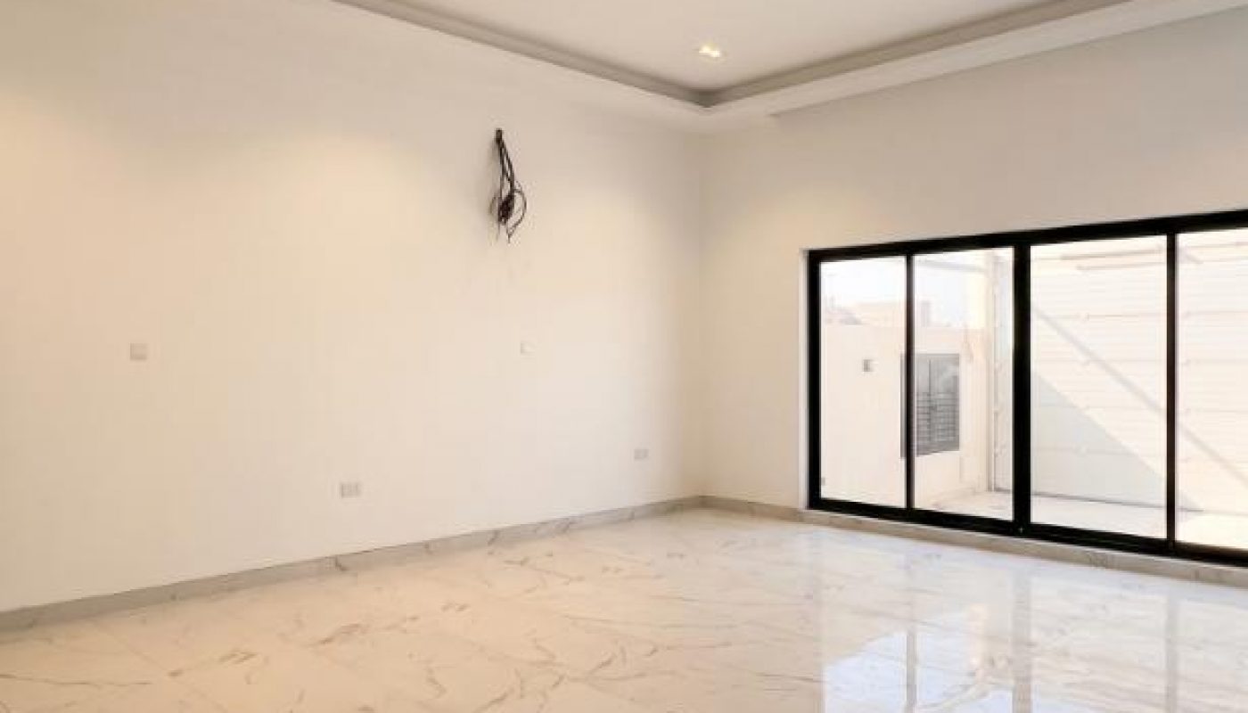 Empty room with white walls, marble tile flooring, recessed ceiling lights, and large sliding glass doors leading outside.