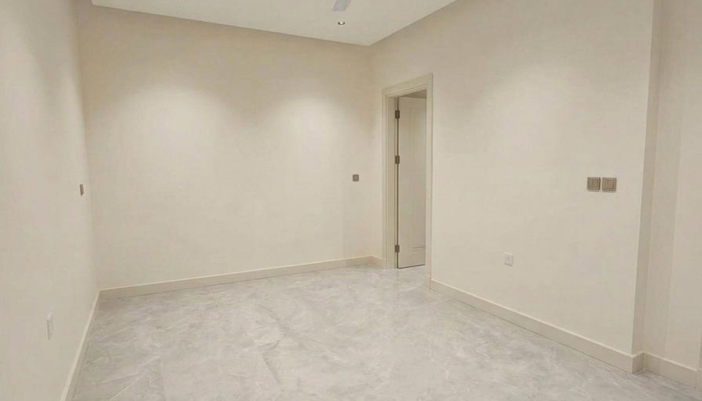 Empty room with light-colored walls, marble floor, ceiling fan, recessed lights, and an open door leading to an adjacent space.