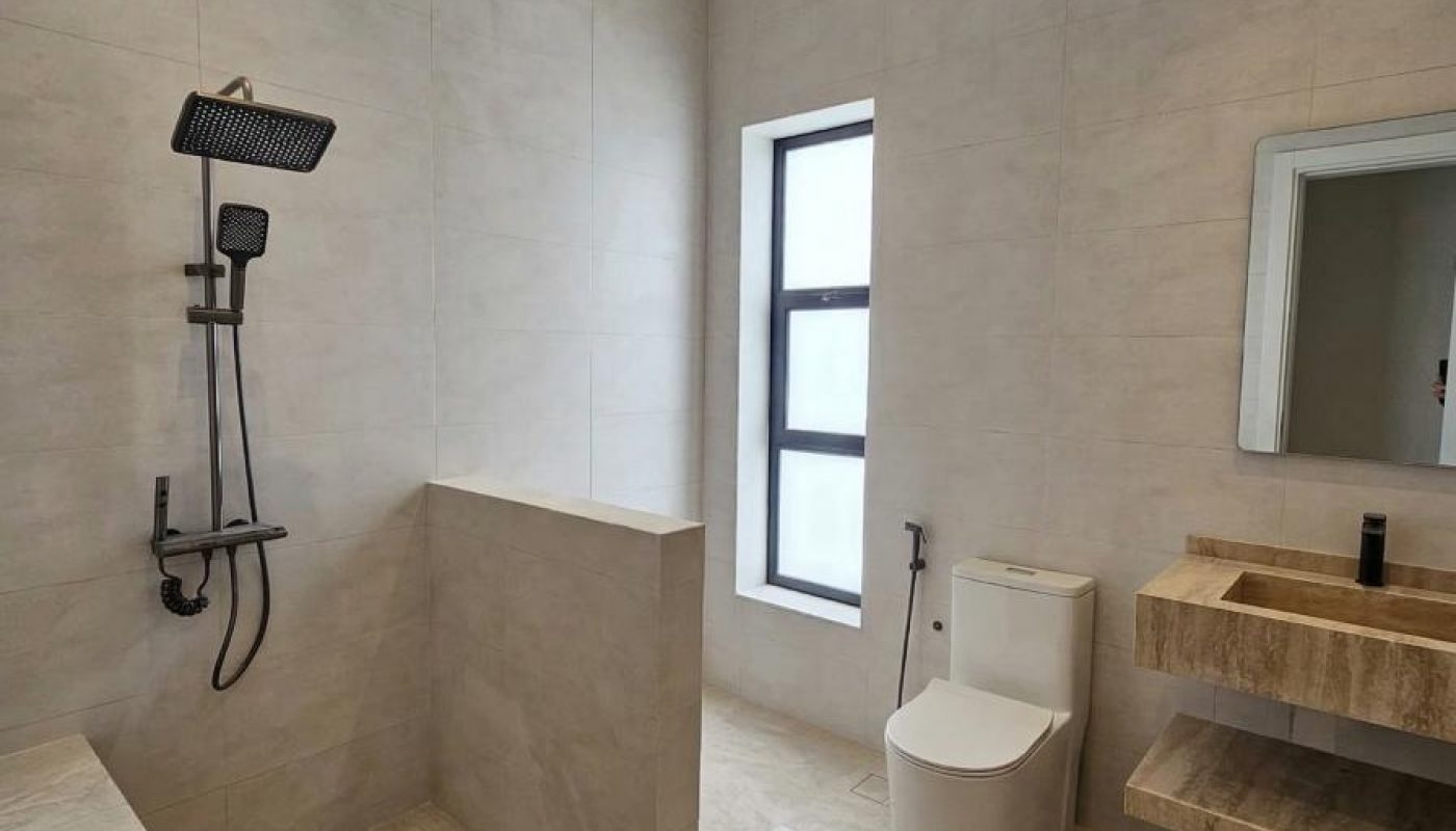 Modern bathroom with a walk-in shower, wall-mounted rainfall showerhead, toilet, rectangular sink, large mirror, and a window letting in natural light.