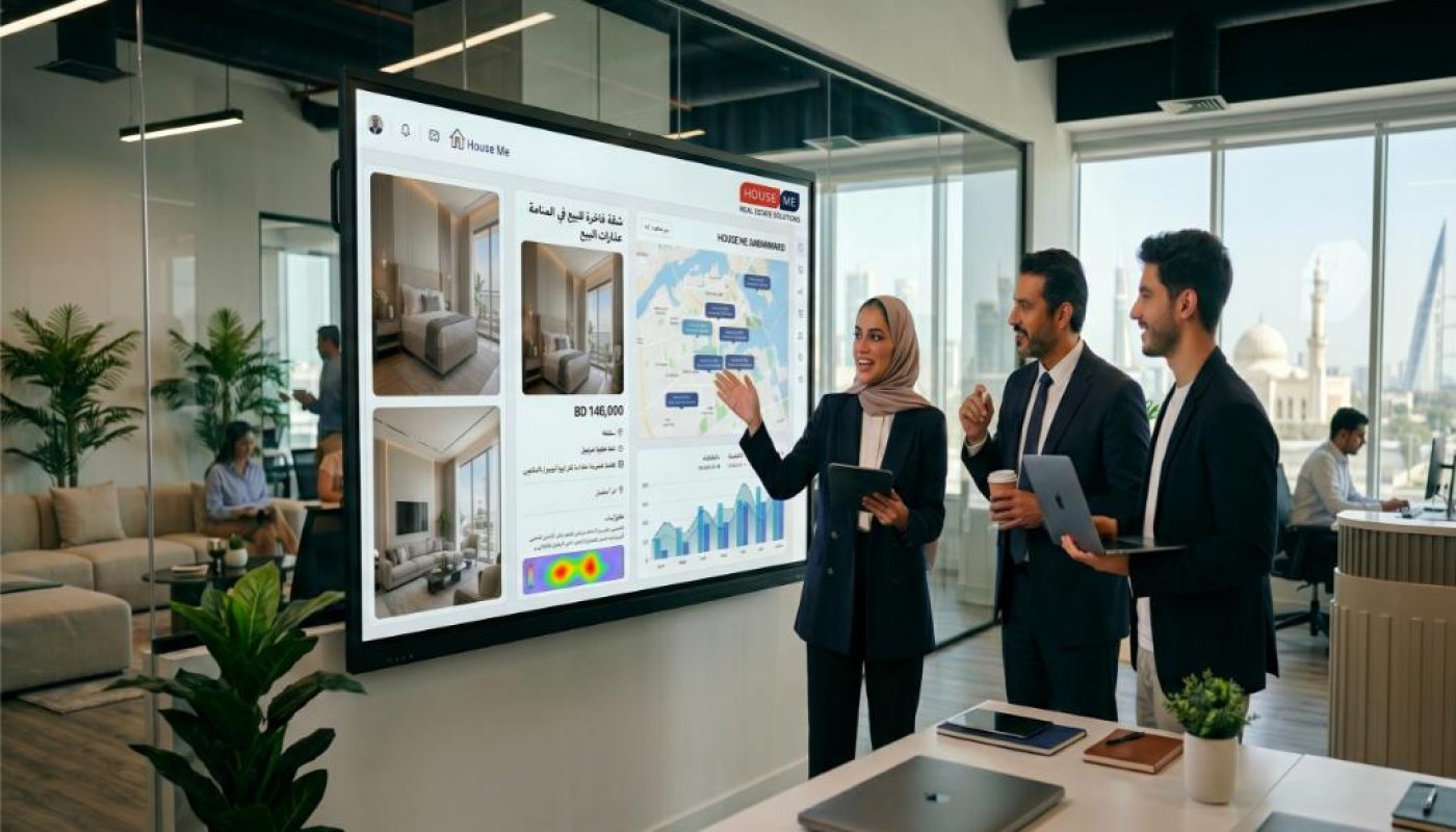 Three business professionals review real estate data and property images on a large digital screen in a modern office conference room.