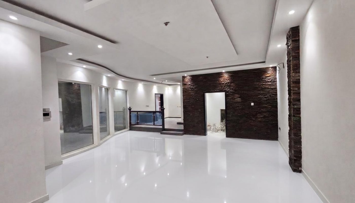 Spacious modern interior with glossy white floors, recessed lighting, sliding glass doors, and dark textured accent walls.