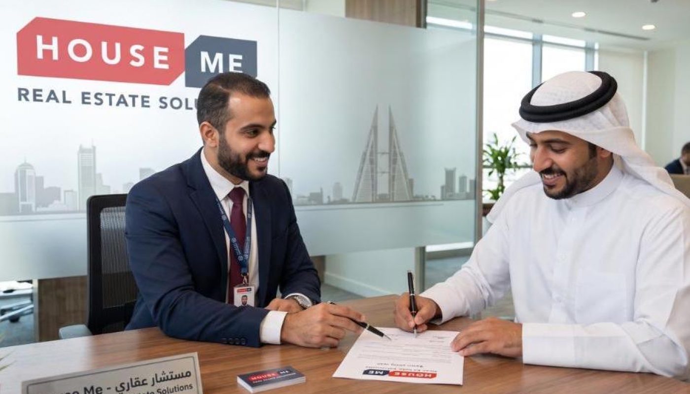 Two men sit at a desk in a modern office. One hands a pen to the other, who signs documents labeled "House Me Real Estate Solutions." City buildings are visible through the window.