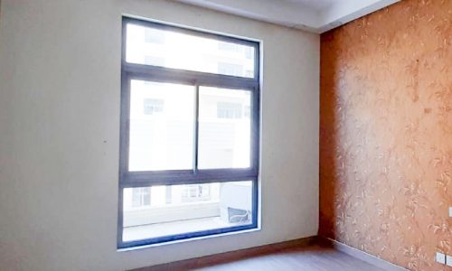 A modern, spacious flat for sale in Isa Town with wooden floors and a window.