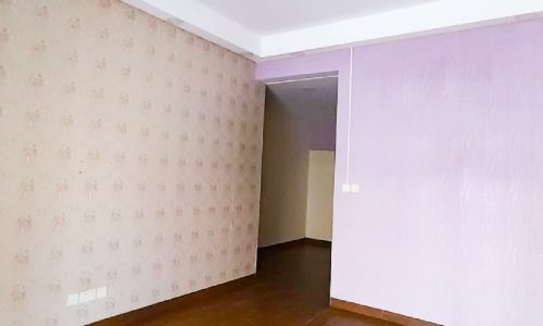 An empty room with modern decor, purple walls, and wood floors.