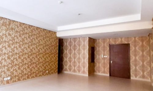 A modern, spacious flat in Isa Town with four bedrooms and an empty room with beige wallpaper and a door.