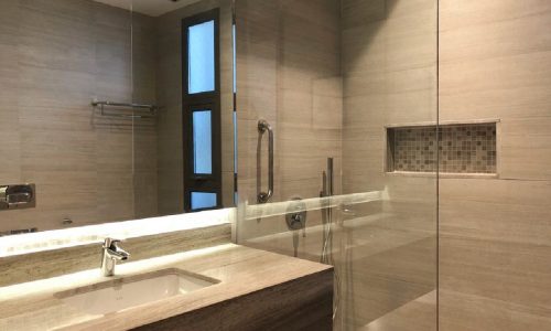 A sophisticated 2BR flat for rent in Janabiyah with a modern bathroom featuring a glass shower stall and sink.