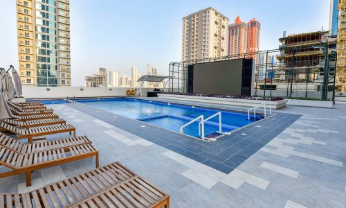 A luxurious residential building with a poolside lounge area surrounded by high-rise structures.