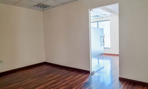 An empty office in the Seef area with softly filtered light and wooden floors.