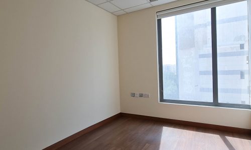 An empty room with wooden floors and a window available for rent.