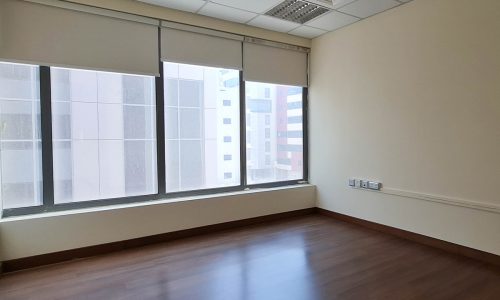 An empty office with stunning wooden floors and large windows.