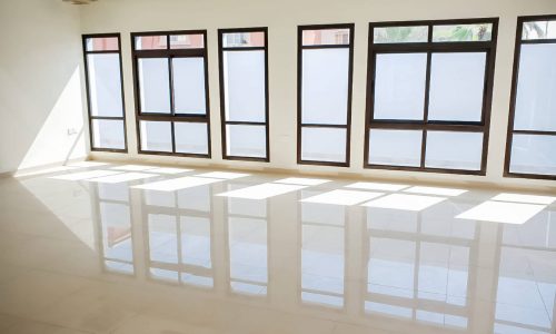 Empty room with large windows and white floor in a luxury villa.