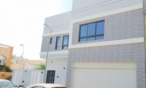 A luxury villa with two cars parked in front of it.