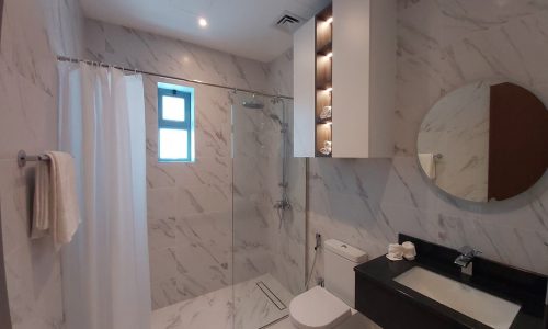 A luxury bathroom with marble walls and a toilet in a 4BR Villa.