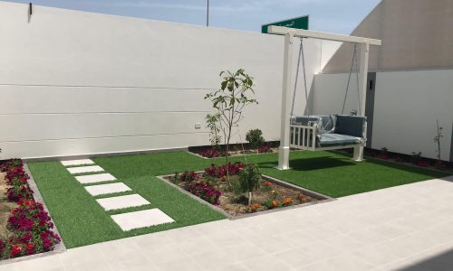 A small garden with a swing and a bench in the luxurious 4BR Villa in Diyar Al Muharraq.