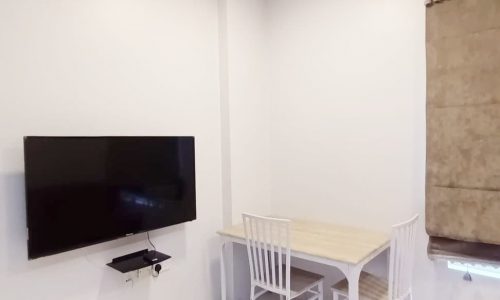 An elegant living room in a small Mahooz apartment with a TV and a table.