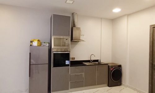 An elegant white kitchen furnished with a refrigerator and microwave.