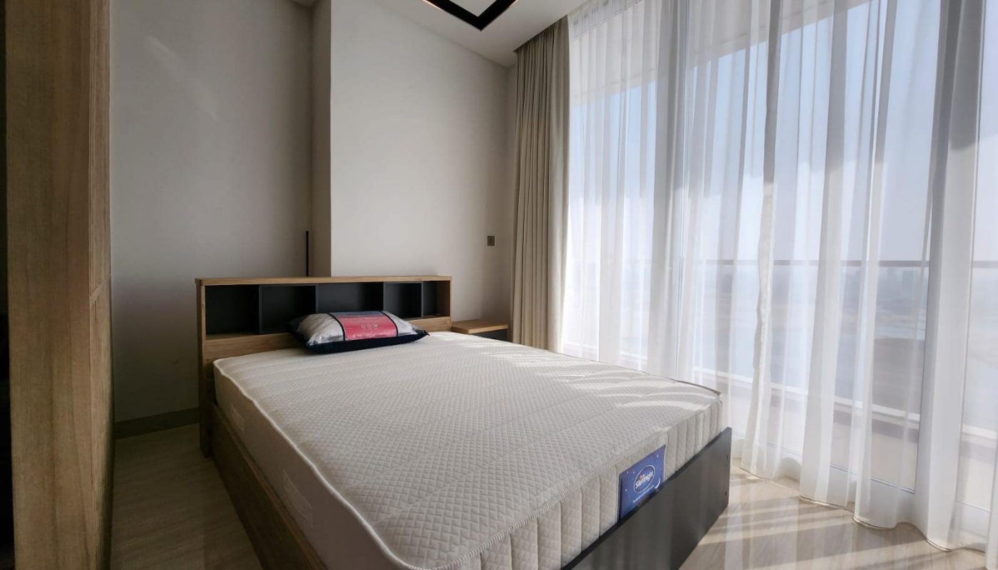 A bed in a Spiral Orchid Residence studio bedroom with a view of the ocean.