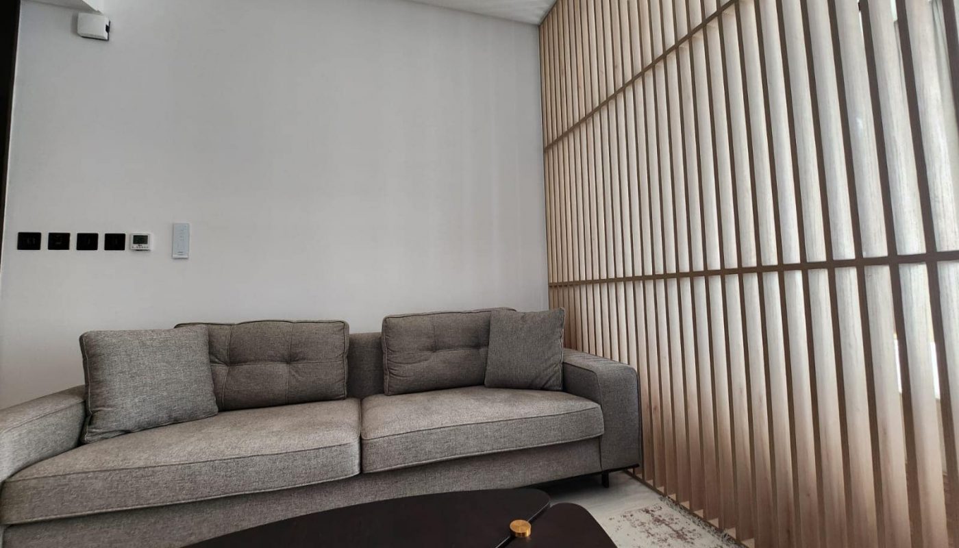 A living room in the Spiral Orchid Residence with wooden slats and a couch.