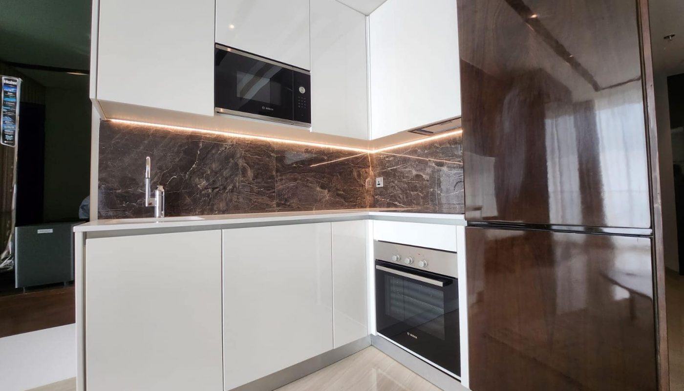 A modern studio kitchen at Spiral Orchid Residence with white cabinets and marble countertops.