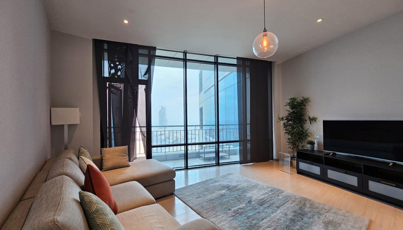 A rental flat in the Seef area featuring a living room with a flat screen TV and a stunning view of the city.