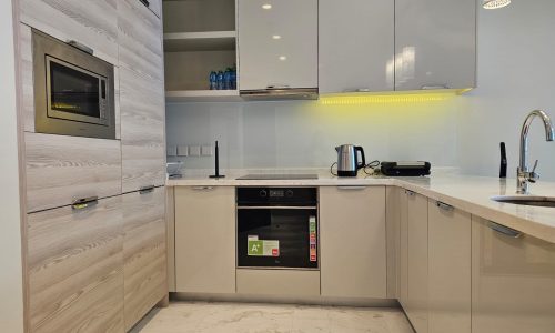 Rent a modern flat in Al Manama with a contemporary kitchen featuring white cabinets and marble counter tops.