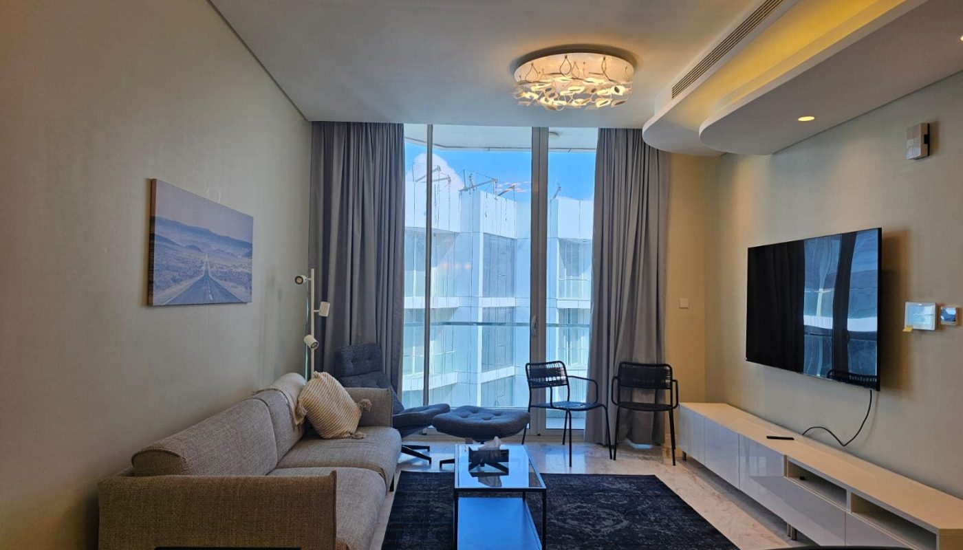 A flat in Almanama for rent, featuring a living room with a flat screen tv and a breathtaking view of the ocean.