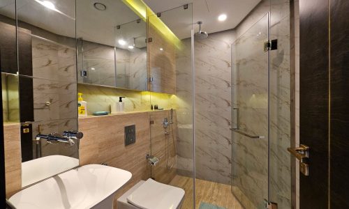 A modern bathroom with a glass shower and toilet is available for rent in a flat in almanama.