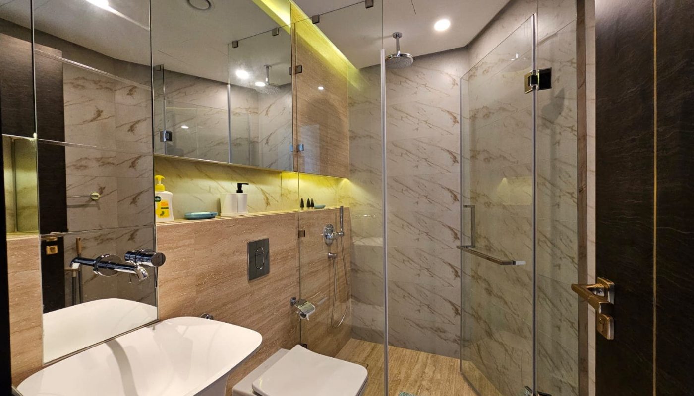 A modern bathroom with a glass shower and toilet is available for rent in a flat in almanama.