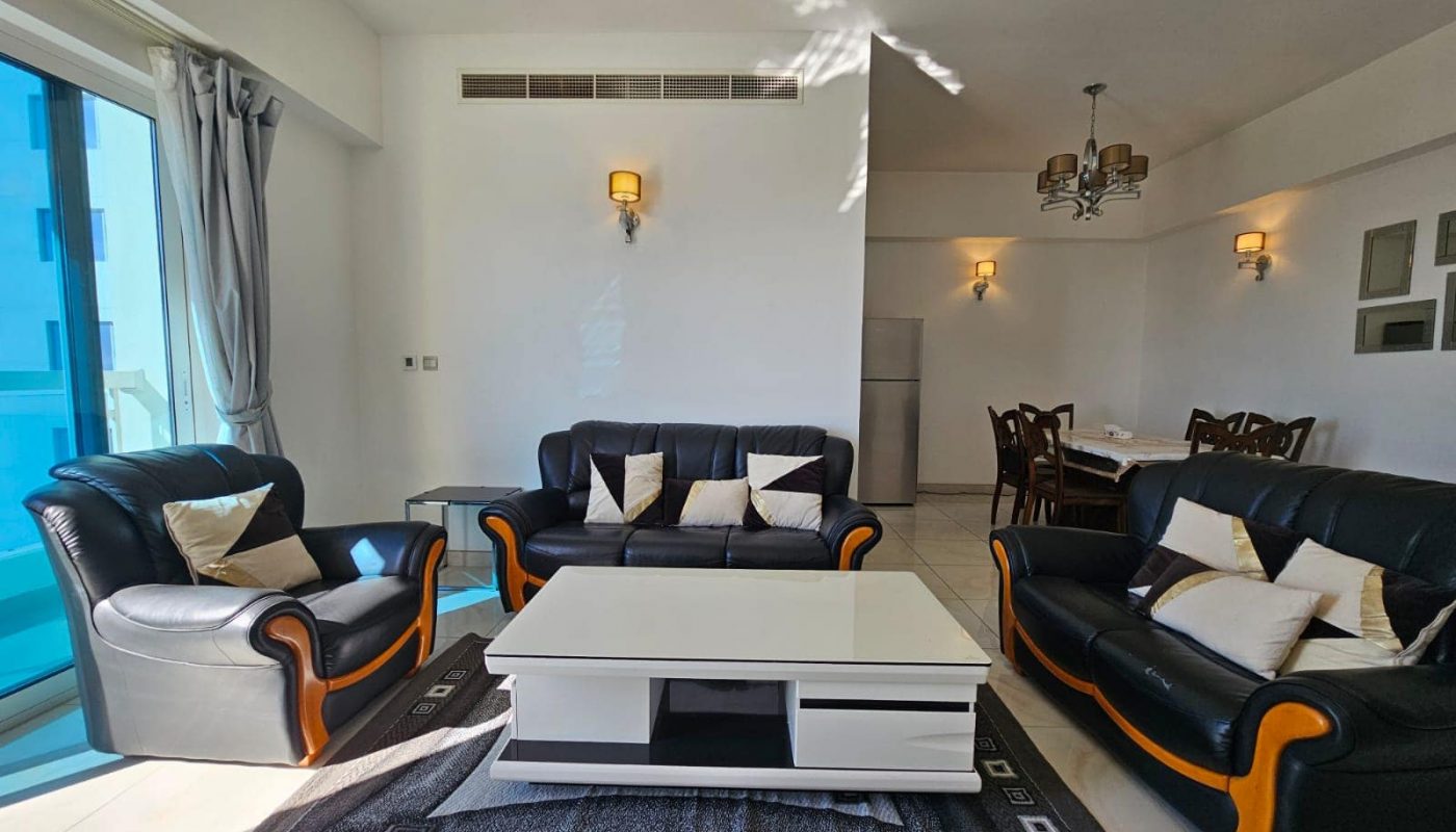 A living room with black leather furniture and a coffee table.
