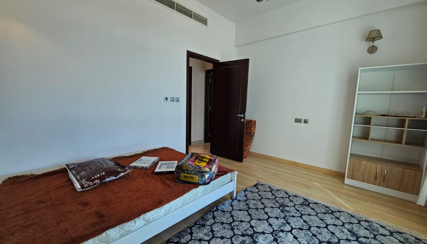 A small bedroom with a bed and a rug.