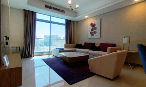 A living room with a couch, coffee table and tv.