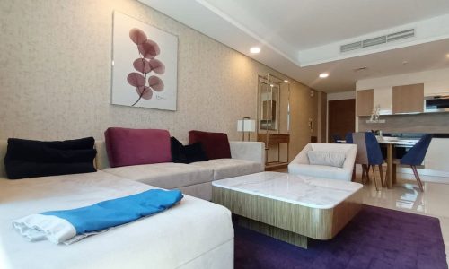 A living room with a purple rug and a coffee table.