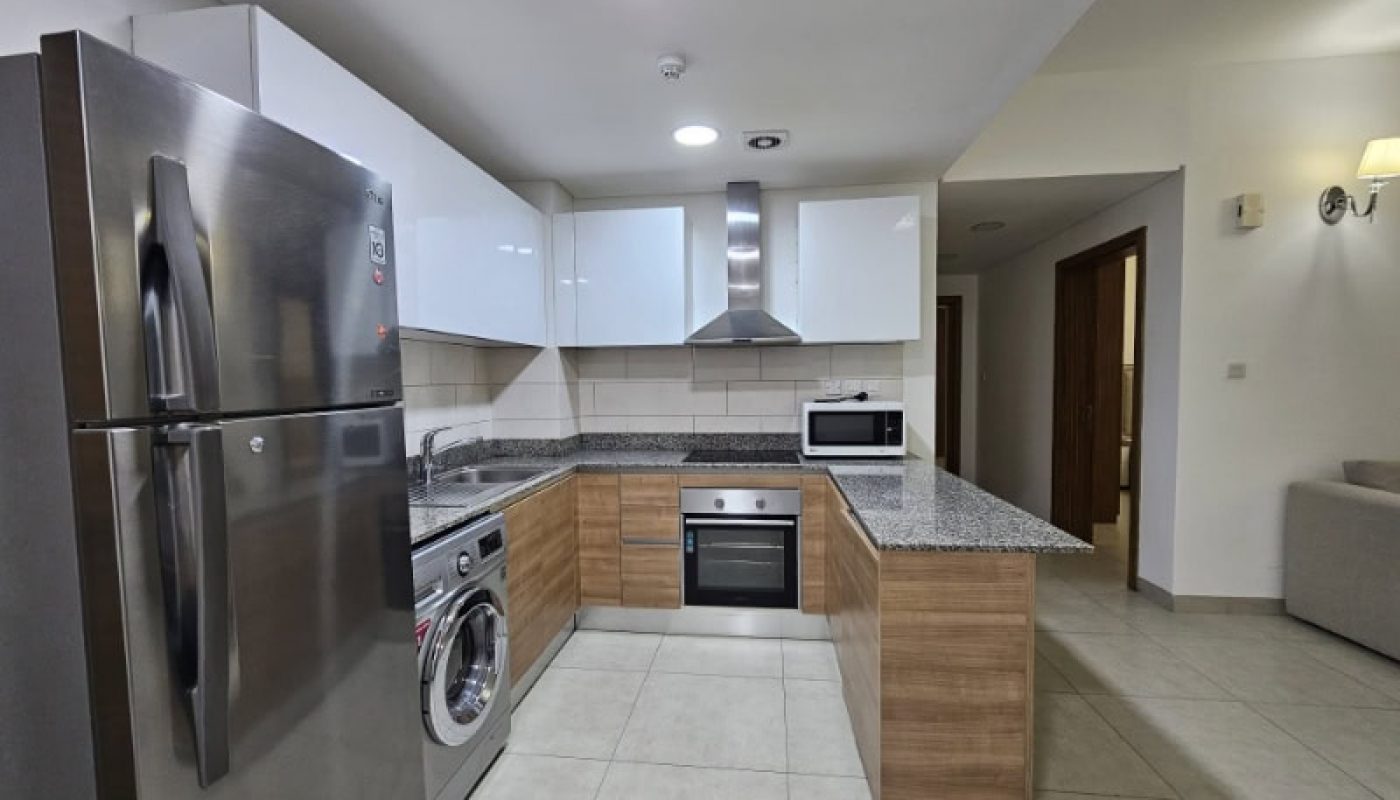 A kitchen in a Juffair flat for rent with a stainless steel refrigerator and oven.