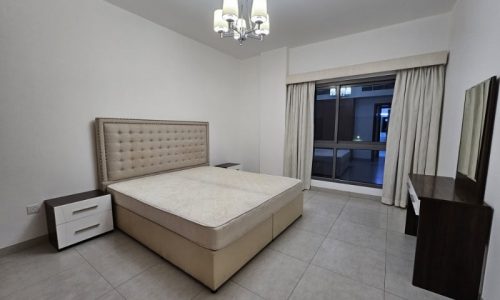 A bedroom with a bed and a dresser available for rent in Juffair.