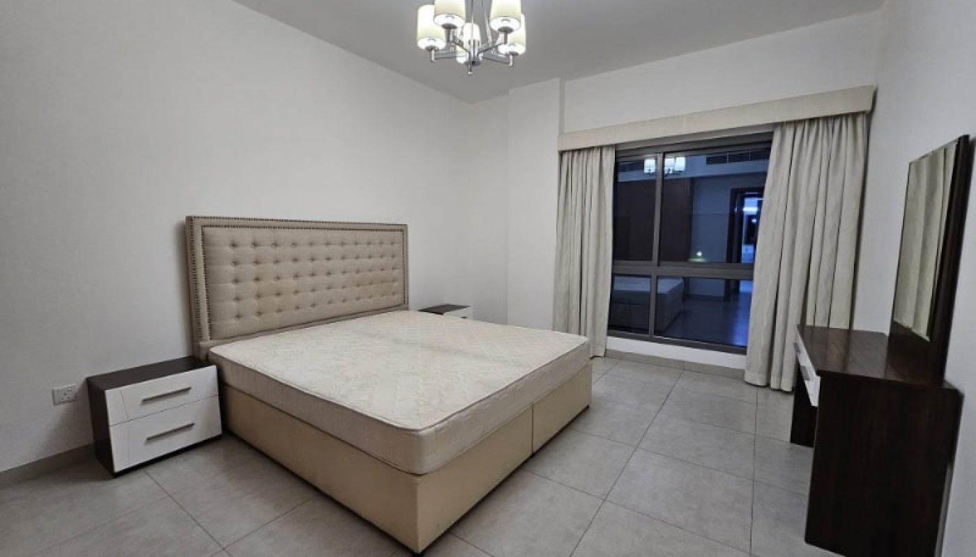 A bedroom with a bed and a dresser available for rent in Juffair.