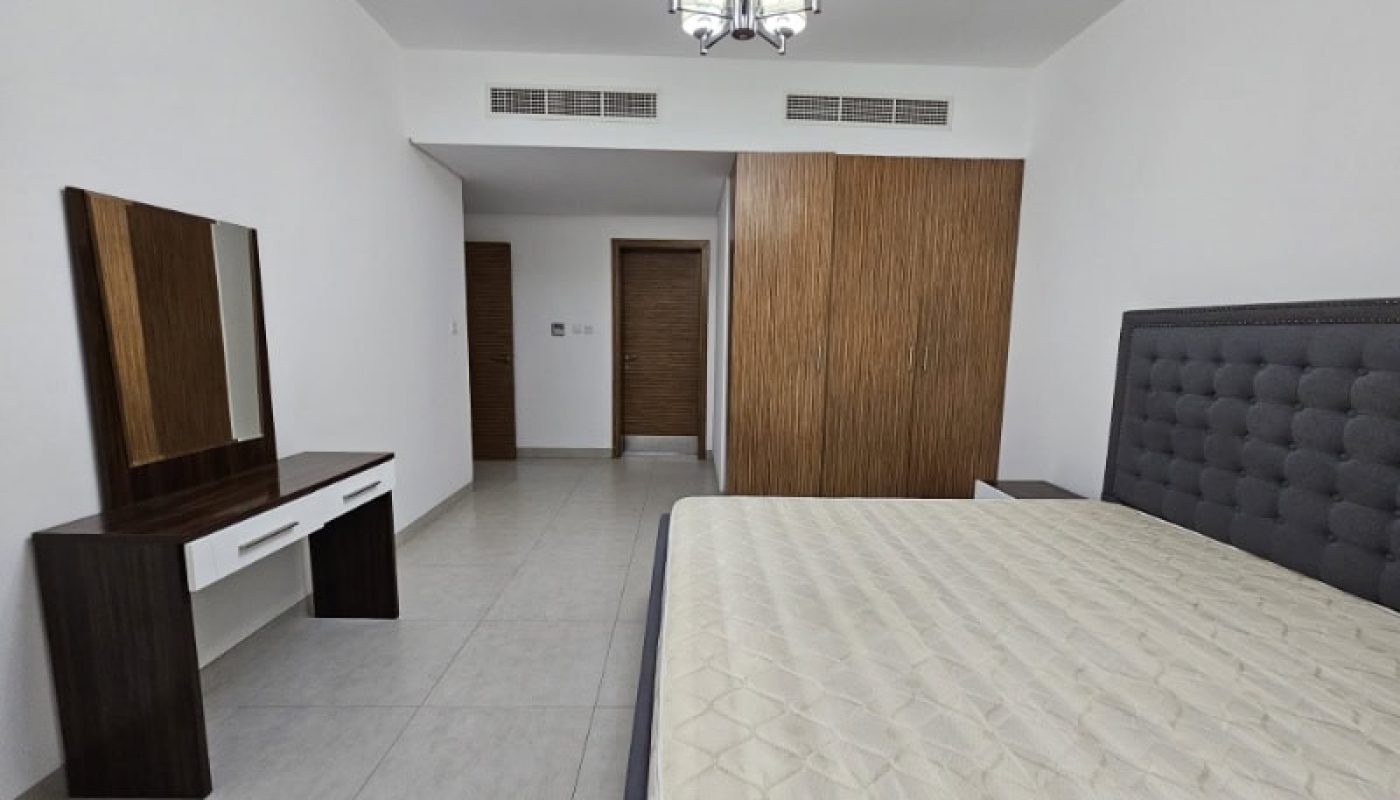 A bedroom for rent in Juffair with a bed, dresser, and mirror.