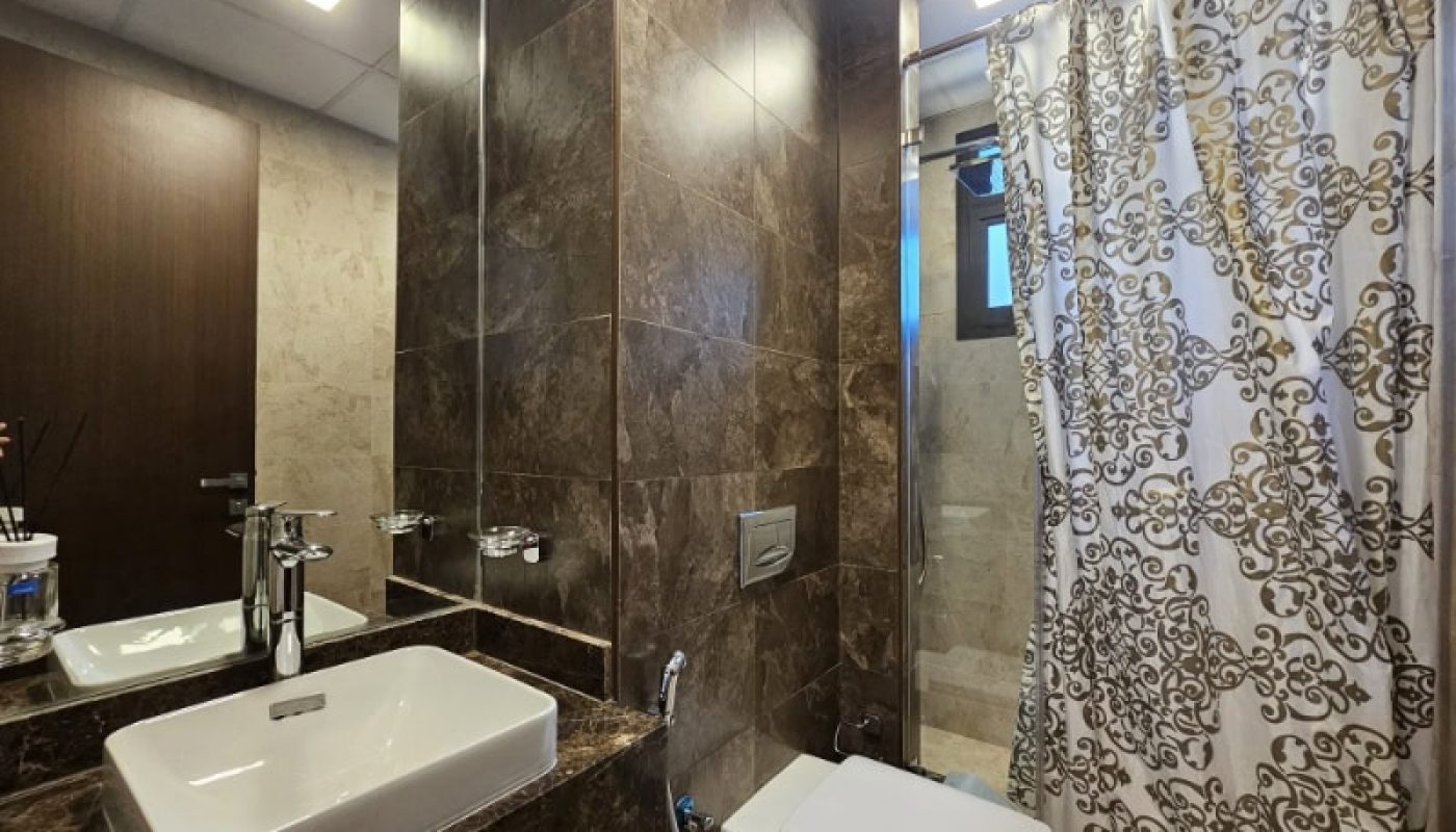 A bathroom with a shower, sink, and toilet in a flat for rent.