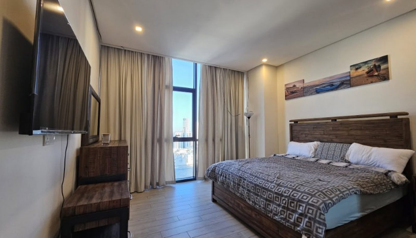 A bedroom in a flat for rent in Juffair with a bed and a tv.