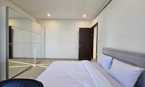 A bedroom with a white bed and mirror.