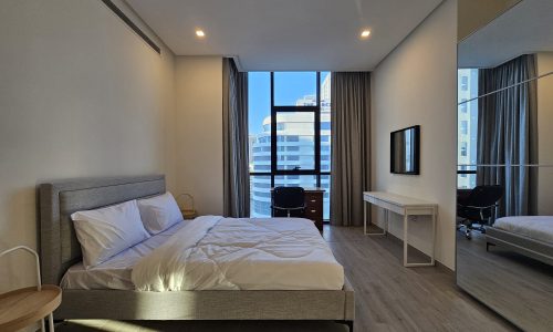 This bedroom offers a view of the city from a large bed.