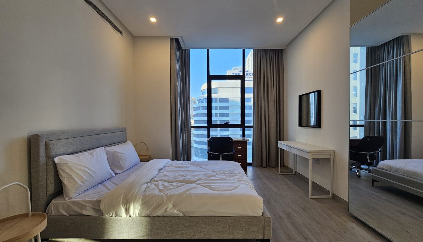 This bedroom offers a view of the city from a large bed.