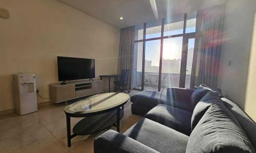 A living room with a cozy couch and a large TV.