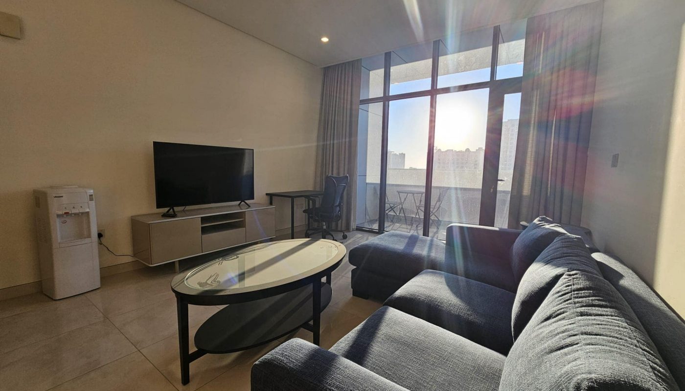 A living room with a cozy couch and a large TV.