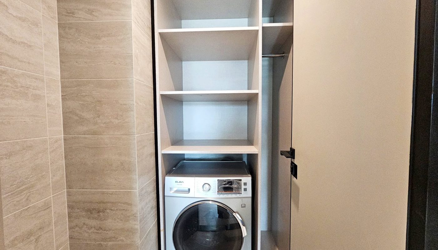 A laundry closet with a washing machine and built-in shelving in a modern home features Auto Draft technology.