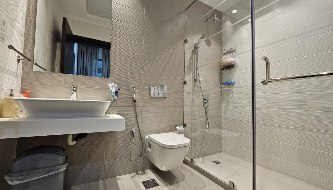 A modern bathroom with an Auto Draft glass shower enclosure, wall-mounted toilet, sink, and mirror.