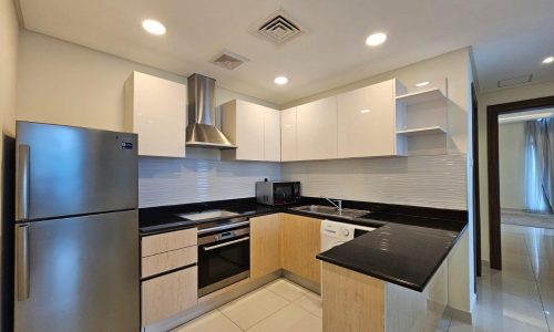 Modern kitchen interior in a luxury apartment for rent, with stainless steel appliances, white cabinetry, and a tiled backsplash.