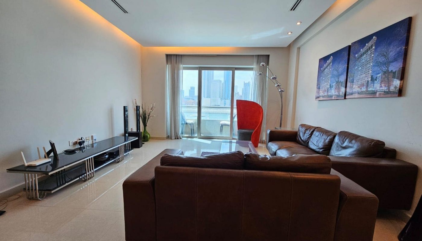 Modern living room with a leather sofa, red armchair, and a city view through the window.