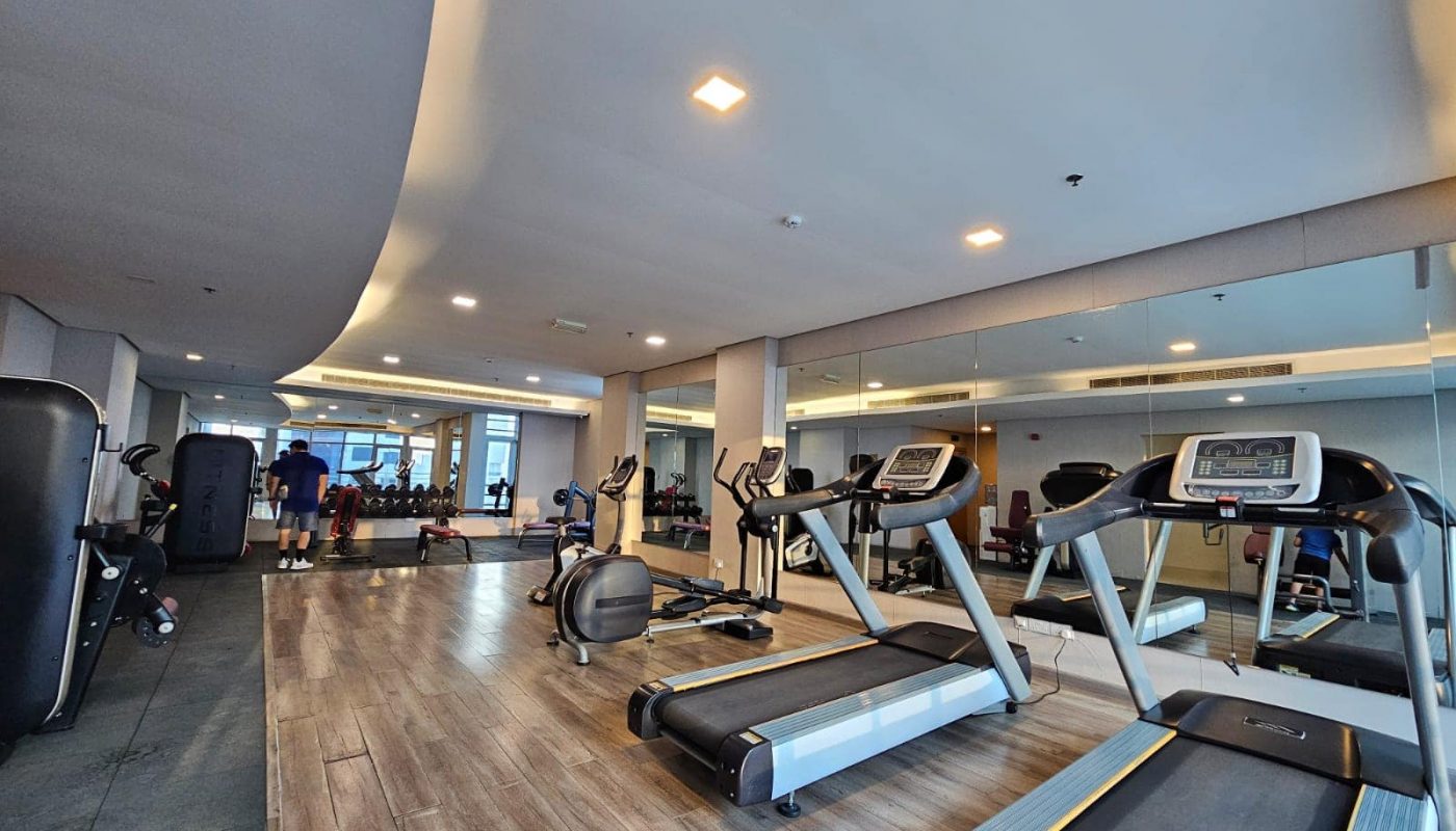 Modern gym interior with various cardio machines, exercise equipment, and Auto Draft system.