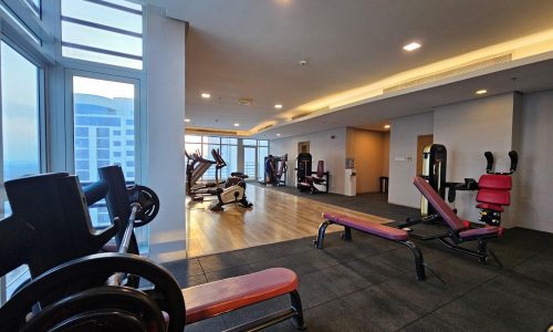 Modern gym with exercise equipment near large windows offering a city view and auto draft.